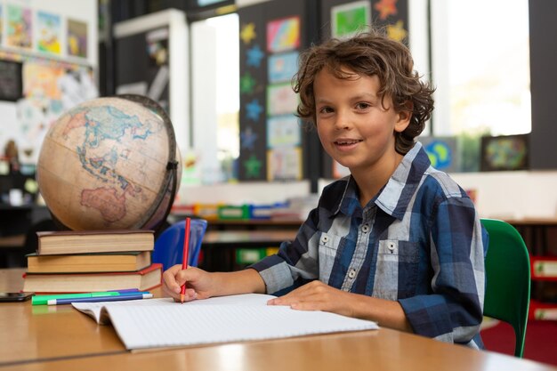 Foto scolaretto che studia alla scrivania in classe