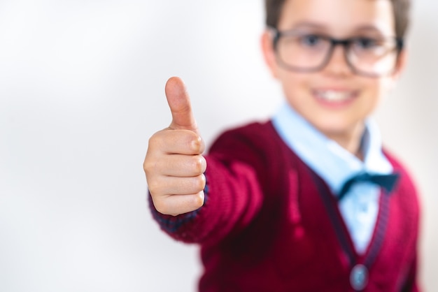 The schoolboy in a sweater shows a thumb up