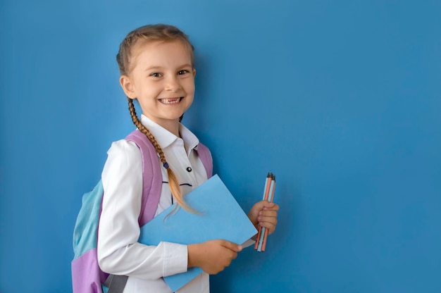 Foto lo scolaro in uniforme tiene lo spazio della copia del taccuino delle matite colorate evidenziato su uno sfondo blu che fa pubblicità alle forniture scolastiche e alla cancelleria di nuovo a scuola interessi di stile di vita hobby tempo libero