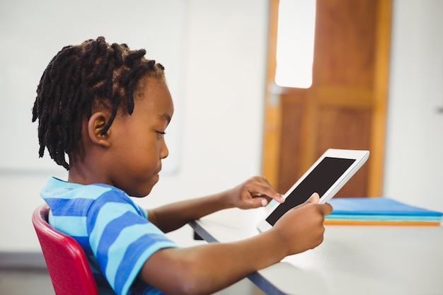 schoolboy using digital tablet in classroom