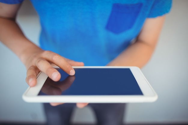 Foto scolaro con tavoletta digitale nel corridoio a scuola