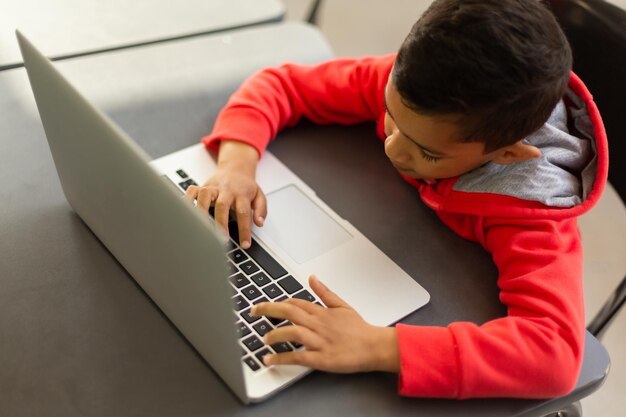 Photo schoolboy using laptop at desk in a classroom