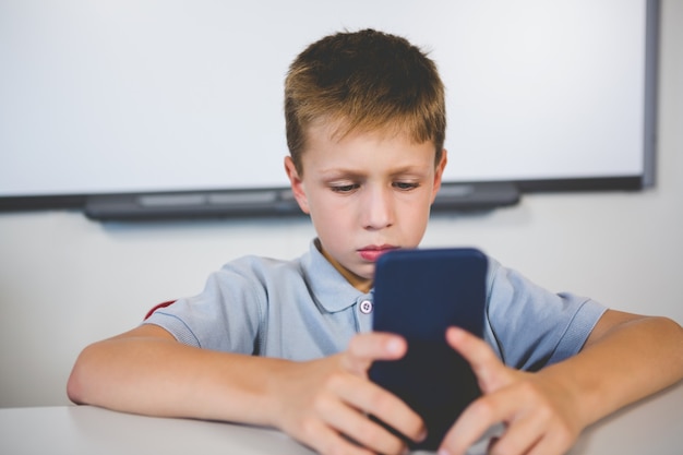 Schoolboy using mobile phone in classroom