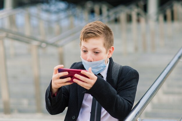 Schoolboy walks out of school wearing protective mask in the city