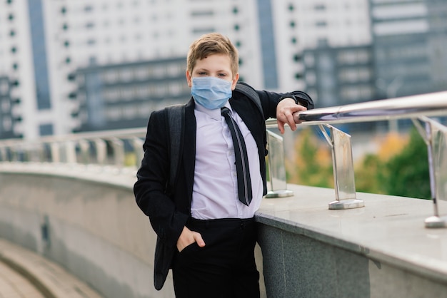 Schoolboy walks out of school wearing protective mask in the city