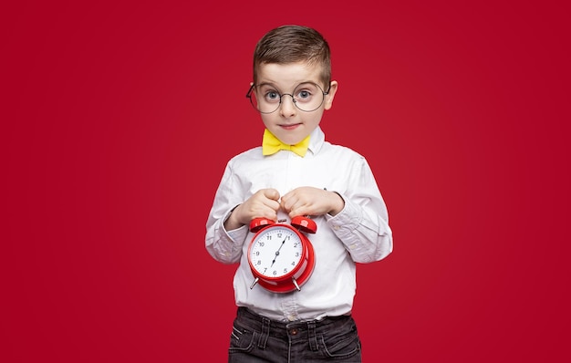 Schoolboy with alarm clock looking at camera