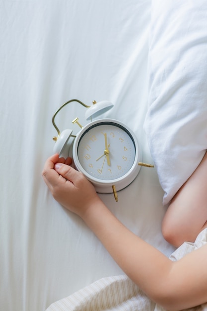 Schoolboy with alarm clock sleeping in bed. Morning.