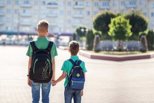 Schoolboys with backpacks going to school. Children and education in the city.