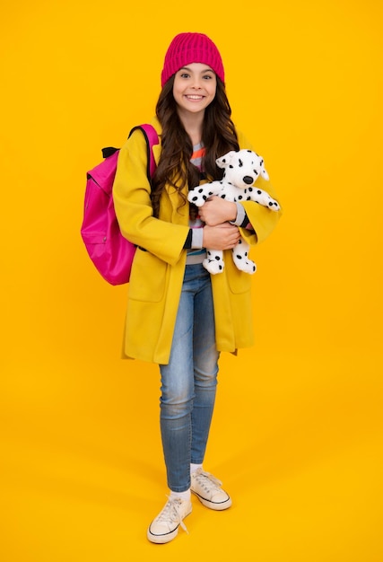 Schoolchild teenage student girl in warm hat with toy on isolated studio background School and education concept Back to school Happy teenager positive and smiling emotions of teen girl