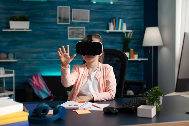 Schoolchild trying virtual reality headset while sitting at desk table