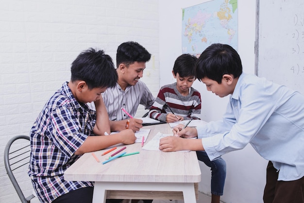 Schoolchildren finishing task from teacher writing on the book together