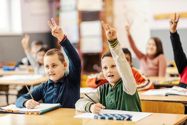 schoolchildren rise arms on class and answer question