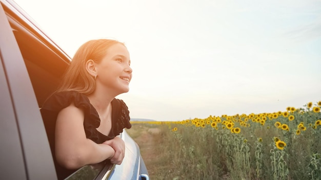 Photo schooler admires sunflowers field smiling from car window