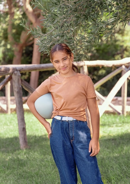 Schooler girl in t-shirt with ball outdoors. Shirt mockup