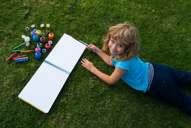 夏の公園の絵画アートで描く小学生の子供たち小さな画家は絵を描く屋外の子供たちの趣味