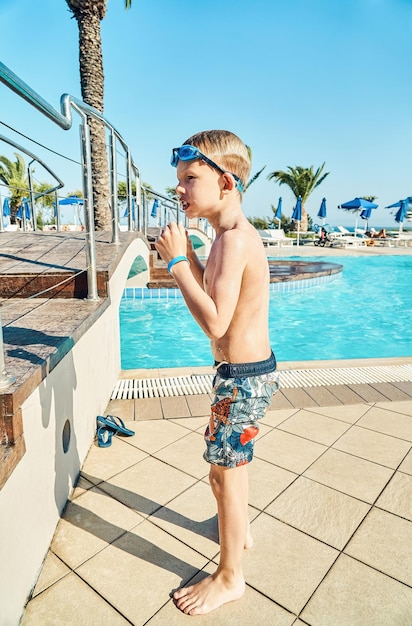 Schooler shivers with cold after swimming in pool with clear blue water on territory of hotel
