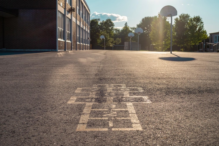 Foto schoolgebouw en schoolplein bij het avondspel hopscotch op de speeltuin van het schoolplein