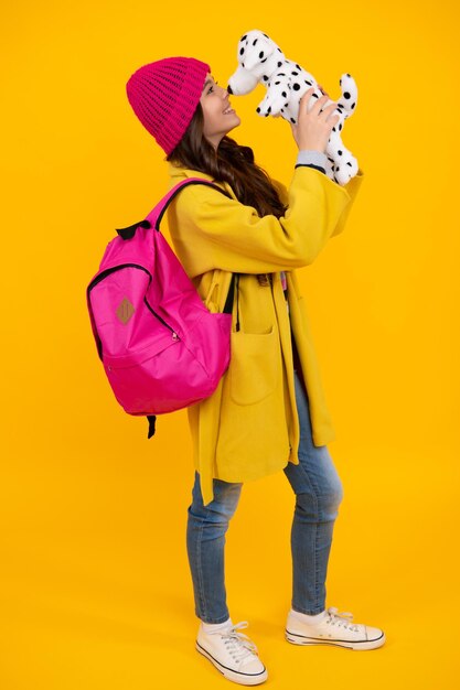 Schoolgirl 12 13 14 years old with toy school children cuddling favorite toys on yellow background happy autumn teenager positive and smiling emotions of teen schoolgirl