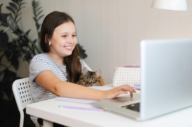 Foto studente in classe con un animale domestico ragazza che fa i compiti con il portatile a casa