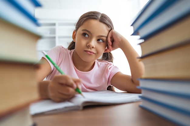 The schoolgirl doing homework at the desk with books