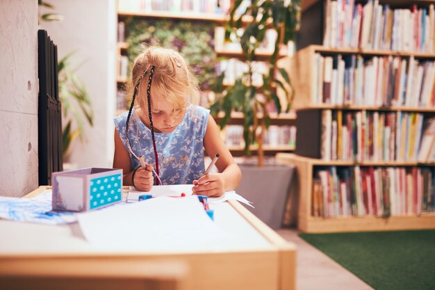 Photo schoolgirl doing homework elementary student learning drawing pictures doing puzzles at desk