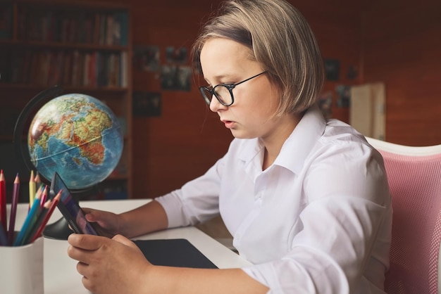 Studentessa impegnata in homeschooling guardando la lezione di apprendimento online sul laptop a casa bambino che frequenta una classe di scuola virtuale remota ascoltando l'insegnante apprendimento remoto a casa con la tecnologia