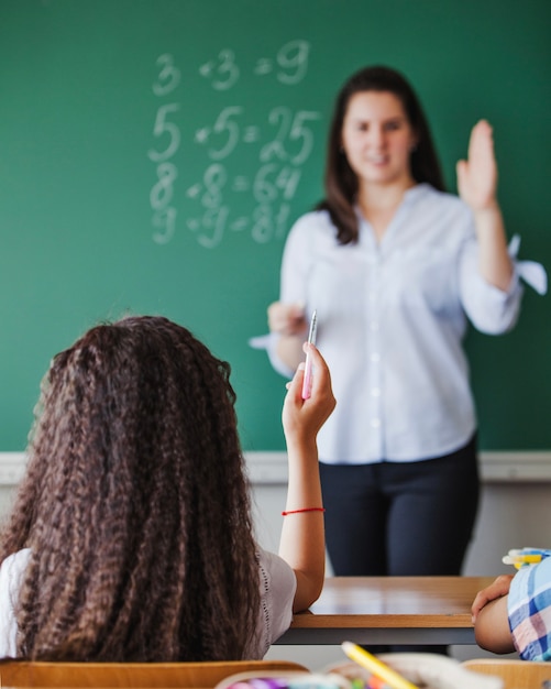 Schoolgirl and female teacher holding hands up