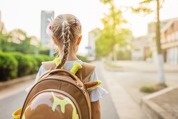 Schoolgirl from behind going to school with backpack