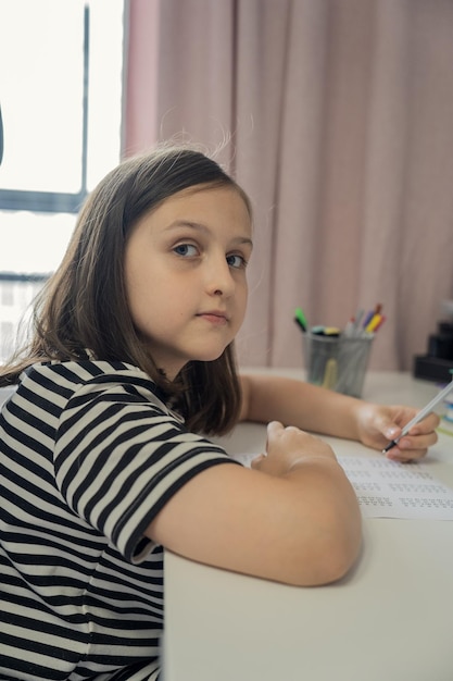 Foto una studentessa fa i compiti a casa. il concetto di ritorno a scuola.