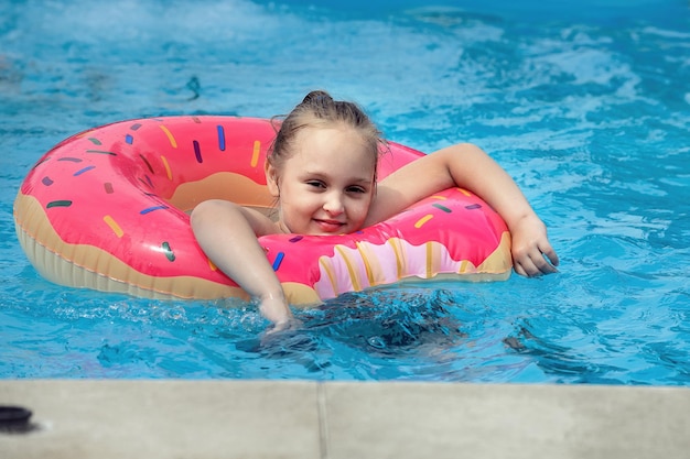 schoolgirl girl having fun on vacation in the outdoor pool in cool water in summer