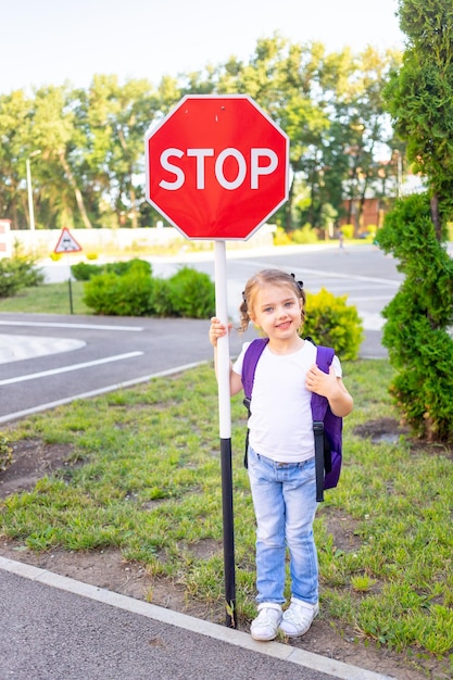 A schoolgirl girl with a STOP sign crosses the road or learns the rules of the road