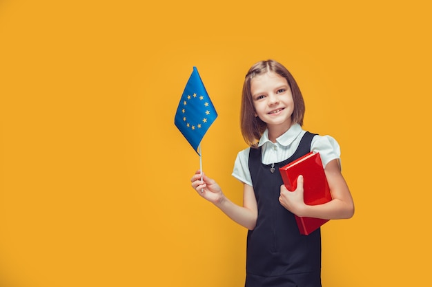 Schoolgirl holding european union flag and book in her hands education in europe concept