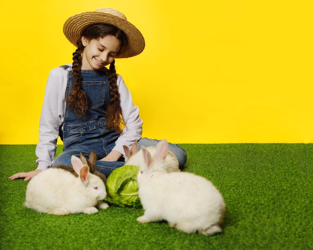 여학생이 스튜디오 노란색 배경에서 토끼와 놀고 누워 있다