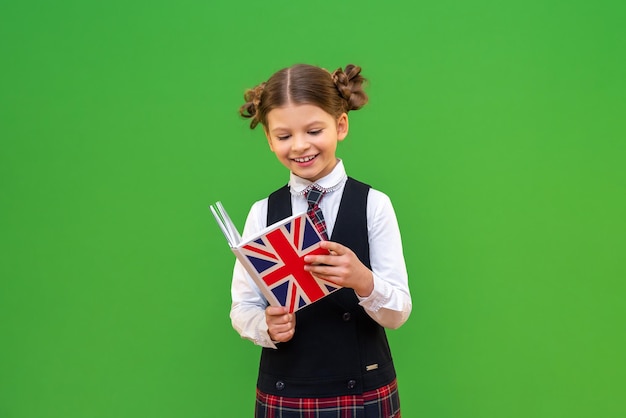 A schoolgirl is reading an english textbook education and
teaching at school isolated green background education in a foreign
school high school homework assignments