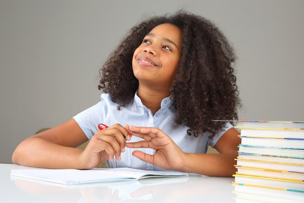 Schoolgirl is thinking about school homework doing homework