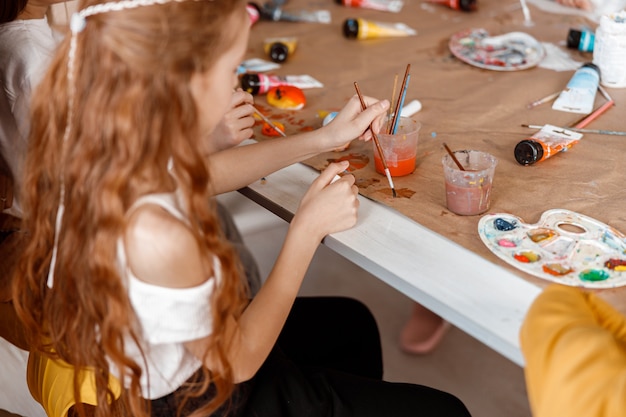 Schoolgirl learning to paint with watercolors at school