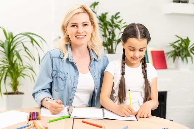 schoolgirl and mother together doing homework in home.