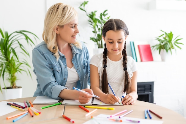 schoolgirl and mother together doing homework in home.