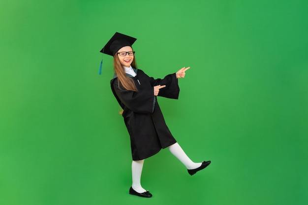 The schoolgirl points to the advertisement and is very happy. A student in the form of a master's degree on a green background, graduation and academic year in high school and obtaining a certificate