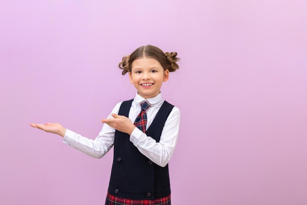 The schoolgirl points to the advertisement and smiles. isolated background. education and schooling. elementary school and lessons.