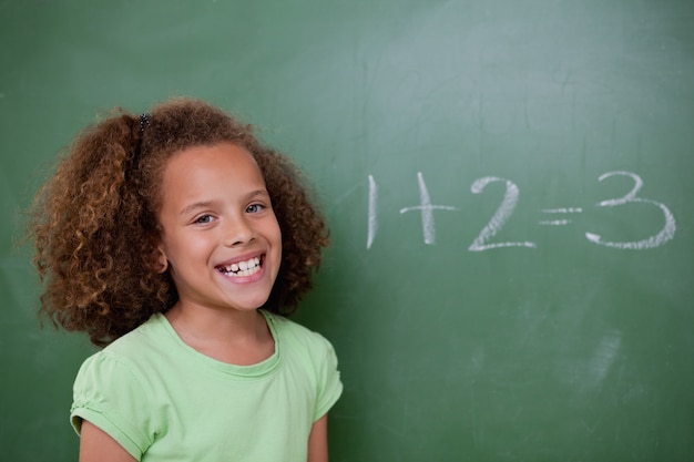 Schoolgirl posing in front of an addition on a blackboard