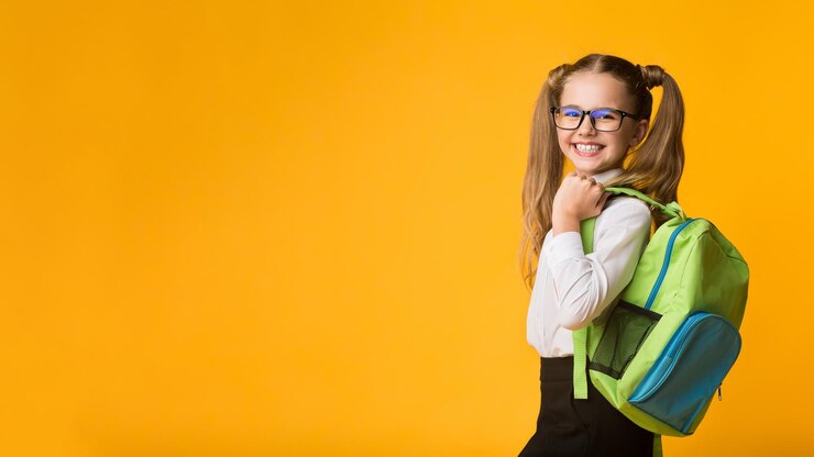 Photo schoolgirl posing with school backpack smiling to camera studio shot