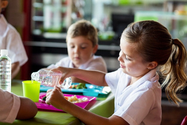 Schoolgirl pouring water in drinking glass