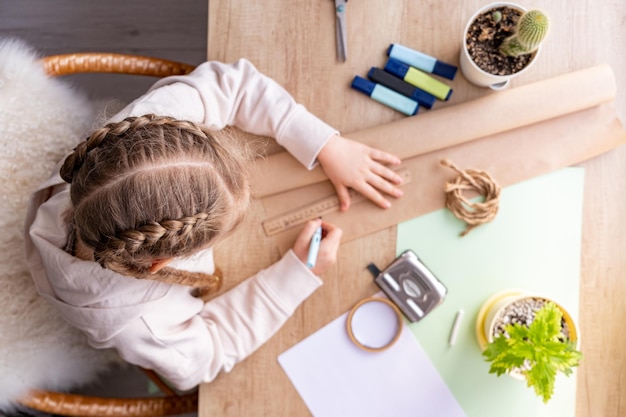 Foto ragazza in età scolare o in età prescolare che fa i compiti a casa o fa artigianato a casa