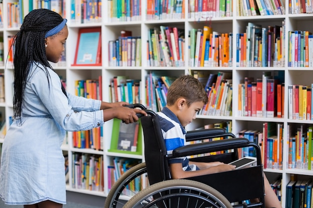 Schoolgirl pushing a boy on wheelchair