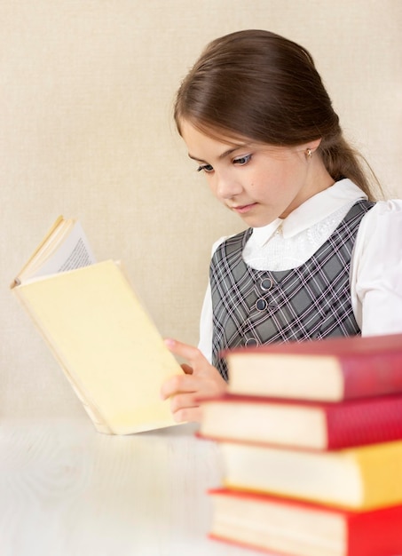 schoolgirl reading a book sitting at the table Side view