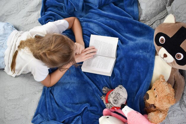 Schoolgirl reading textbook on the bed