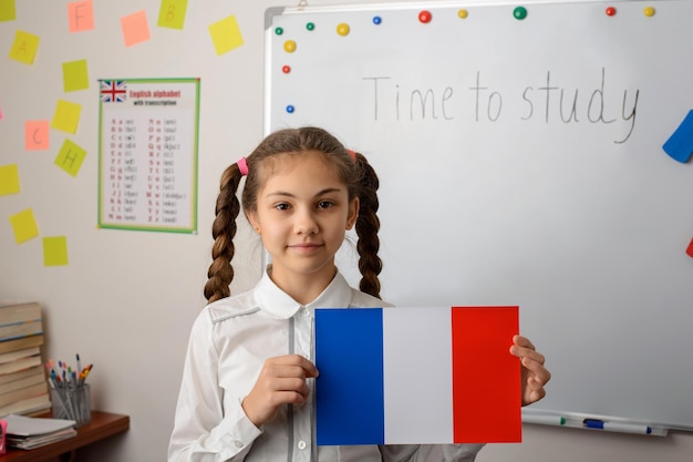 Schoolgirl in school classroom with french flag near the whiteboard