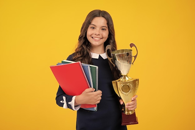 Schoolgirl in school uniform celebrating victory with trophy teen holding winning award prize