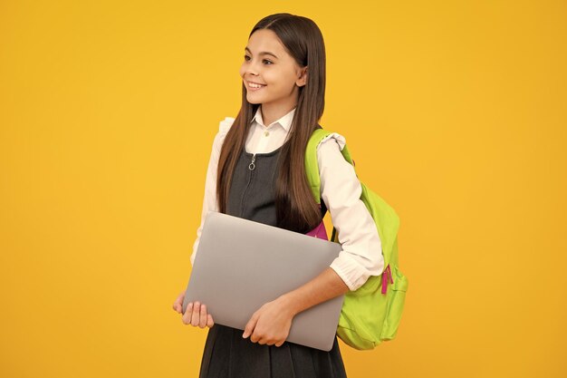 노트북과 교복을 입은 여학생 노란색 격리 된 배경에 학생 십대 학생 행복한 소녀 얼굴 긍정적이고 웃는 감정